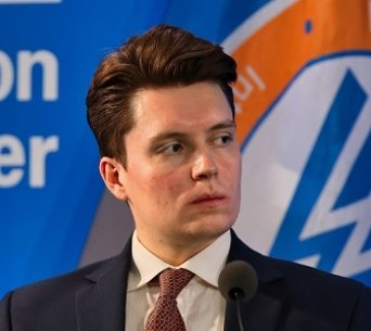 A photo of Lucas Myers speaking at a conference with the Wilson Center logo in the background.