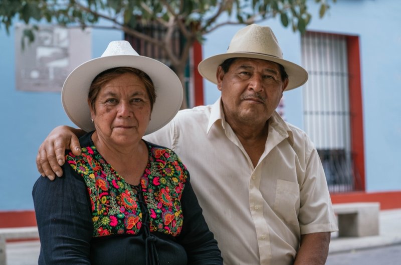 Latin couple of grandparents, sitting outdoors in colorful streets of Oaxaca, Mexico.
