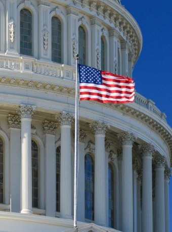 US Capitol Building dome detail with waving national flag - Washington DC, United States of America