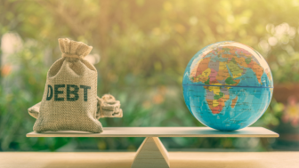 A globe and bag marked 'debt' balance on a scale