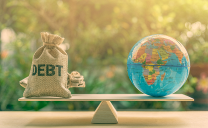 A globe and bag marked 'debt' balance on a scale