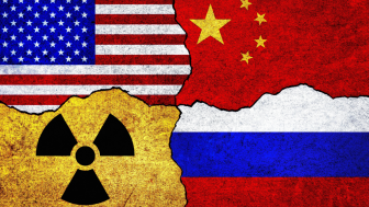 Flags of USA, Russia, China and radiation symbol on a wall.